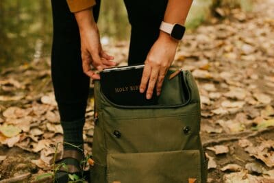 A woman takes her Bible from her backpack.