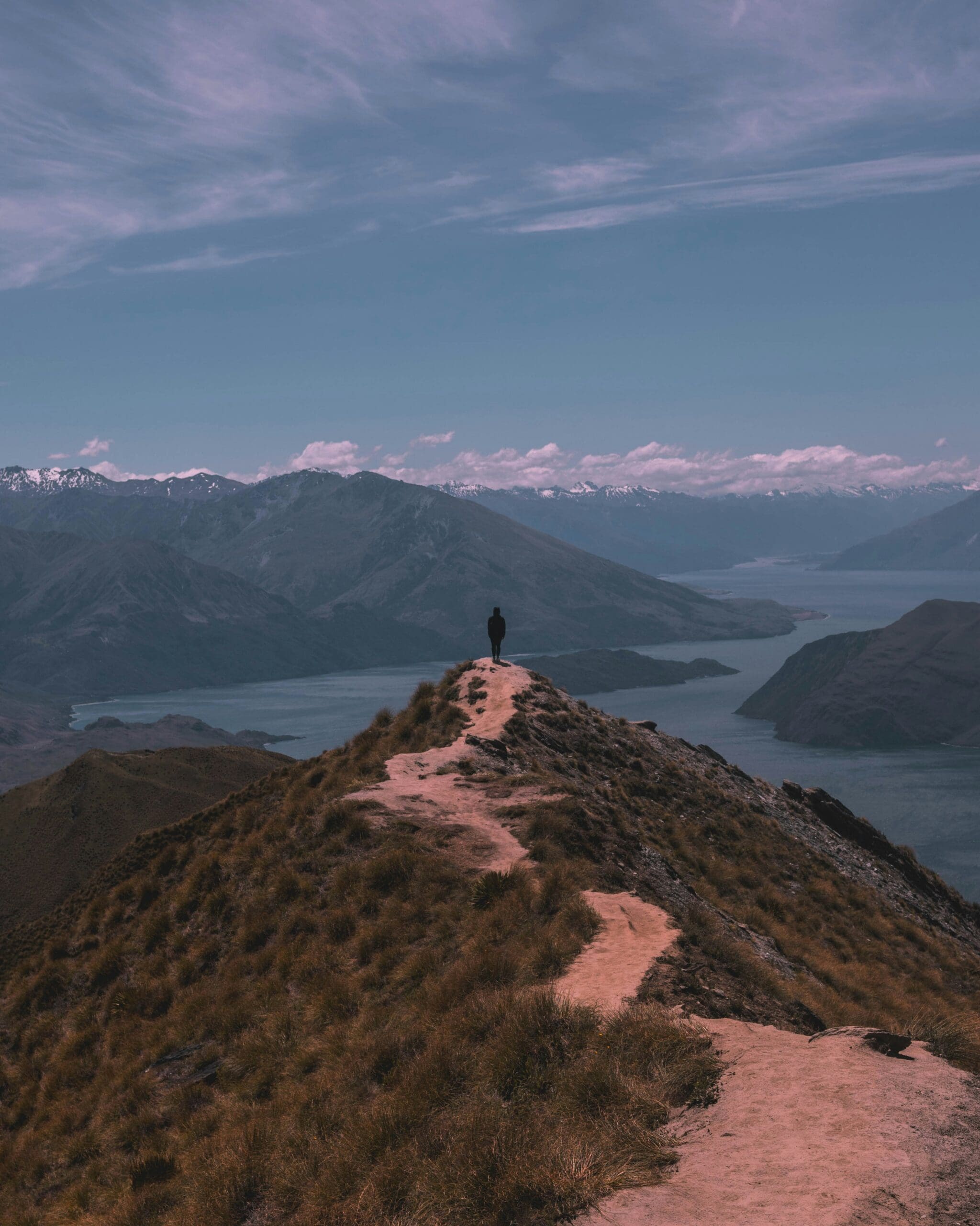 A person looks out over a beautiful mountain lake at the end of a path.